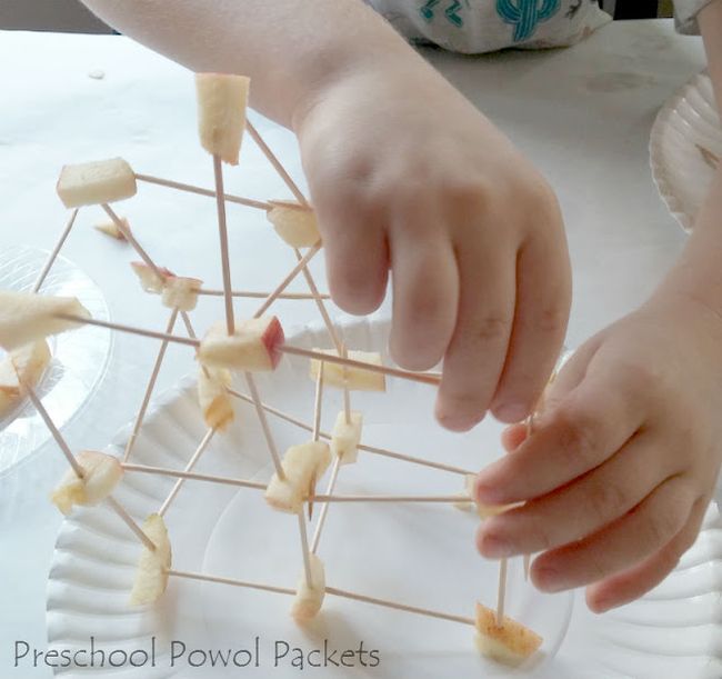 Preschool science student using toothpicks and apple pieces to build a tower